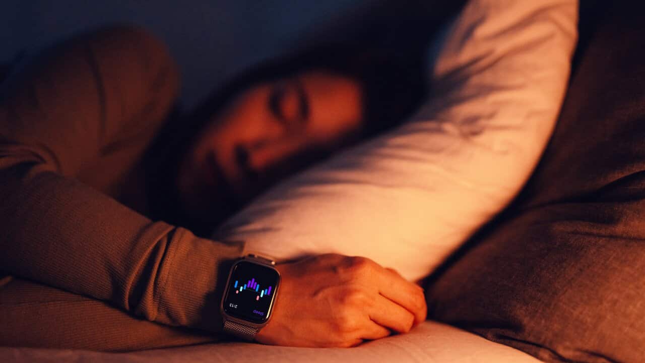 A woman lying in bed asleep. A smartwatch is visible on her wrist.