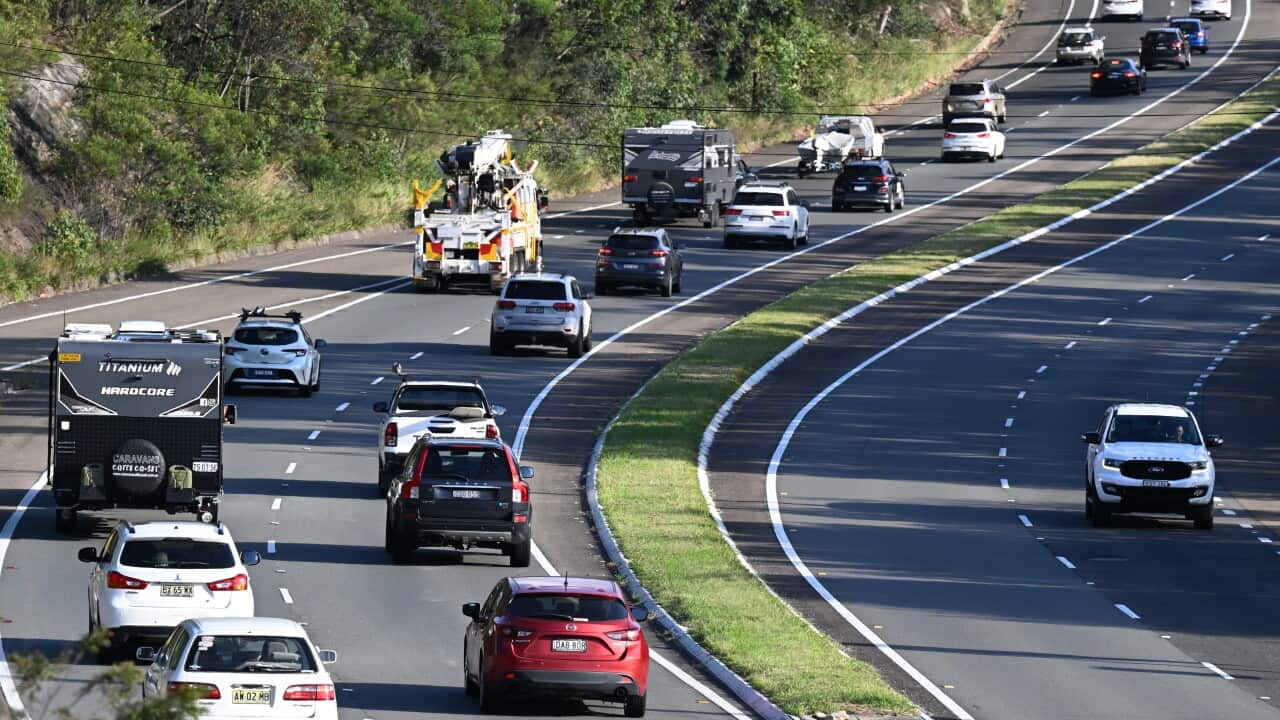 A multi-lane arterial road with lanes carrying traffic travelling in different directions separated by a median strip. Lots of vehicles are travelling in one direction, while very few are travelling in the other direction.