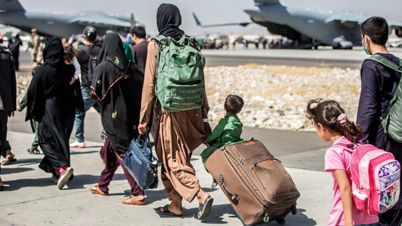In this Aug. 24, 2021, file photo, provided by the U.S. Marine Corps, families walk towards their flight during ongoing evacuations at Hamid Karzai International Airport, in Kabul, Afghanistan.