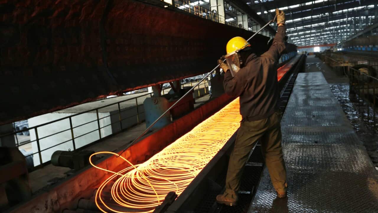 A Chinese worker surveys the production of coiled steel rods.