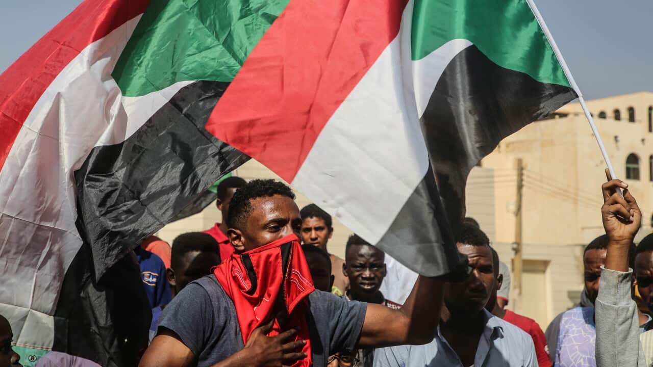Sudanese protesters hold the national flag and chant during a demonstration in the capital Khartoum, 25 October 2021