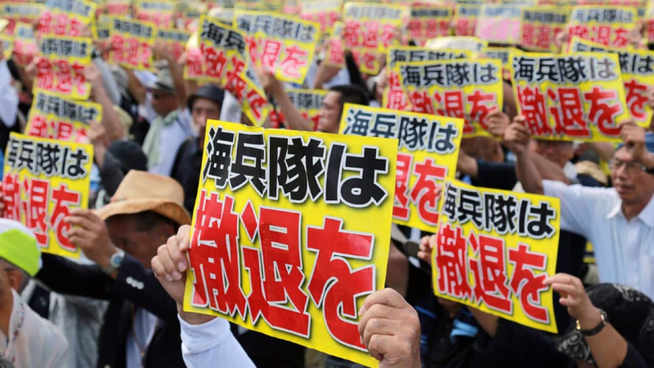 Protesters hold placards reading Marines withdraw, Okinawa