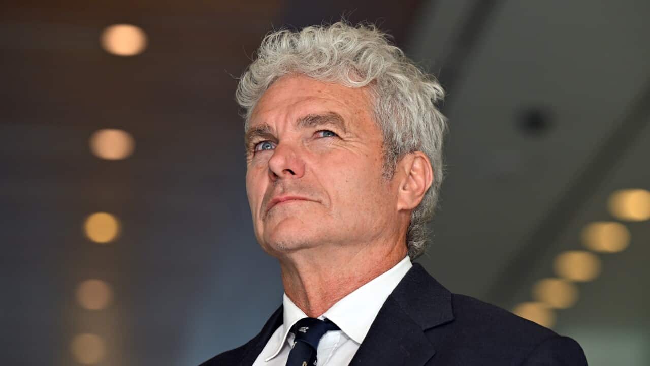 A man in a suit with grey hair looking into the distance