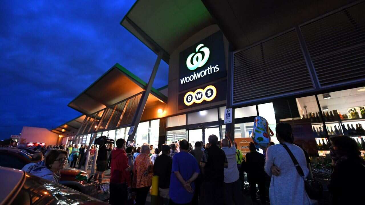 People are seen waiting outside a Woolworths supermarket in Coburg, Melbourne
