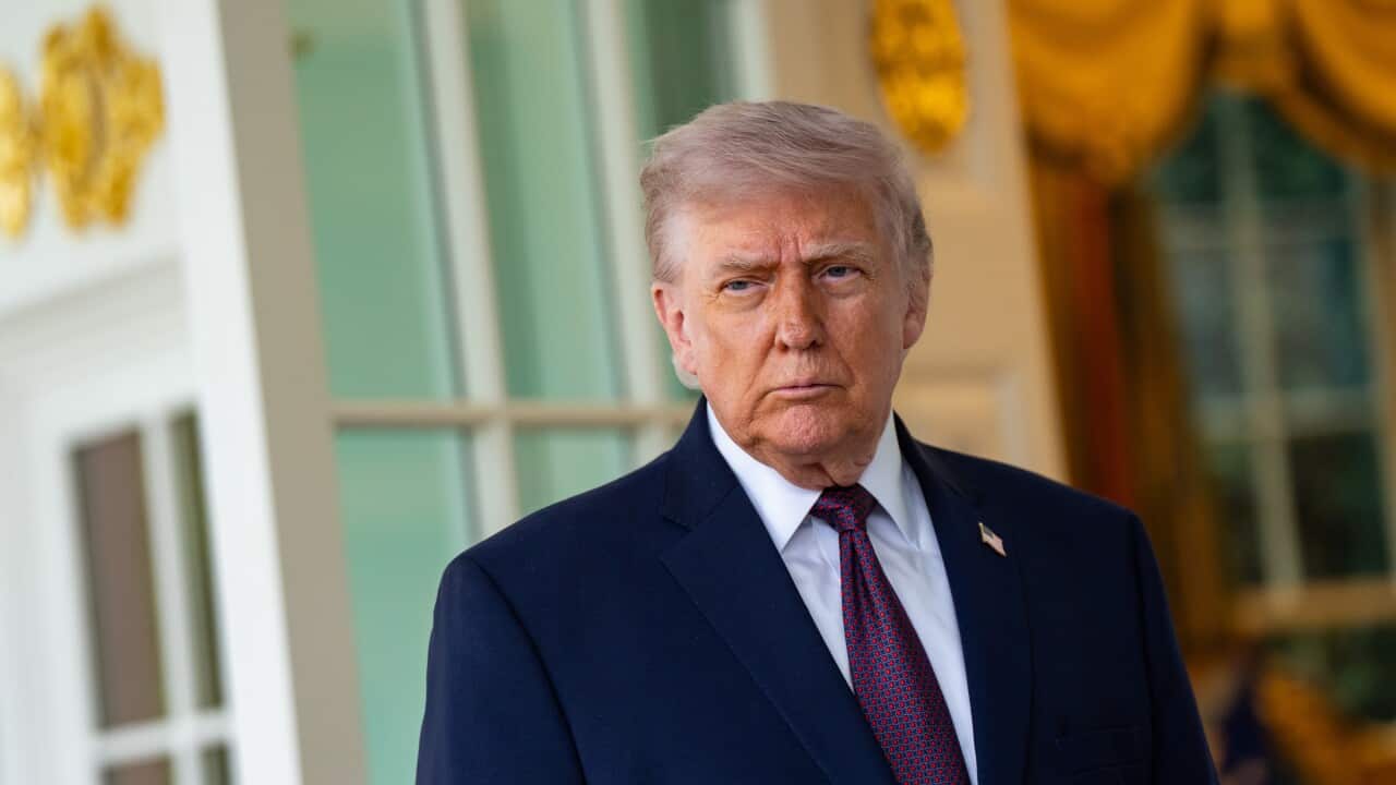 An older white man with blonde hair and wearing a dark suit
