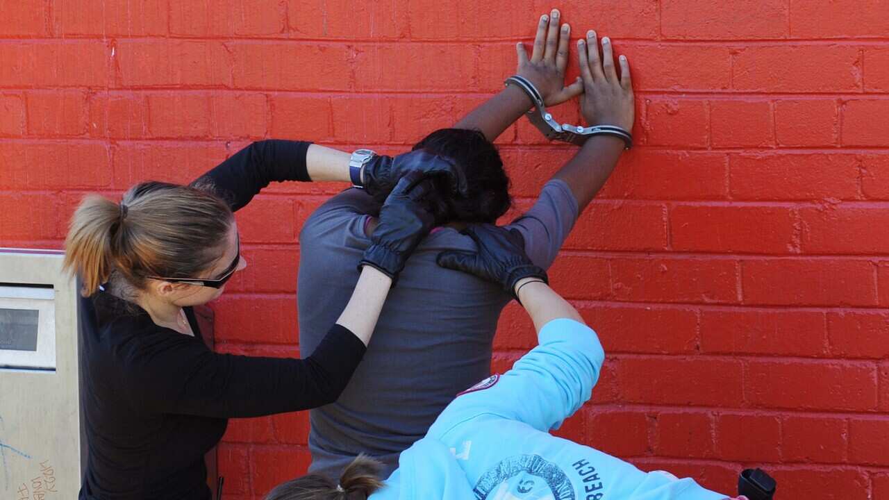 Police officers search a woman in Redfern, Sydney