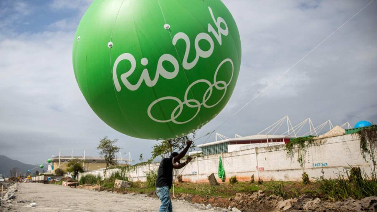 A worker carries huge balloons next to the Olympic Park in Barra
