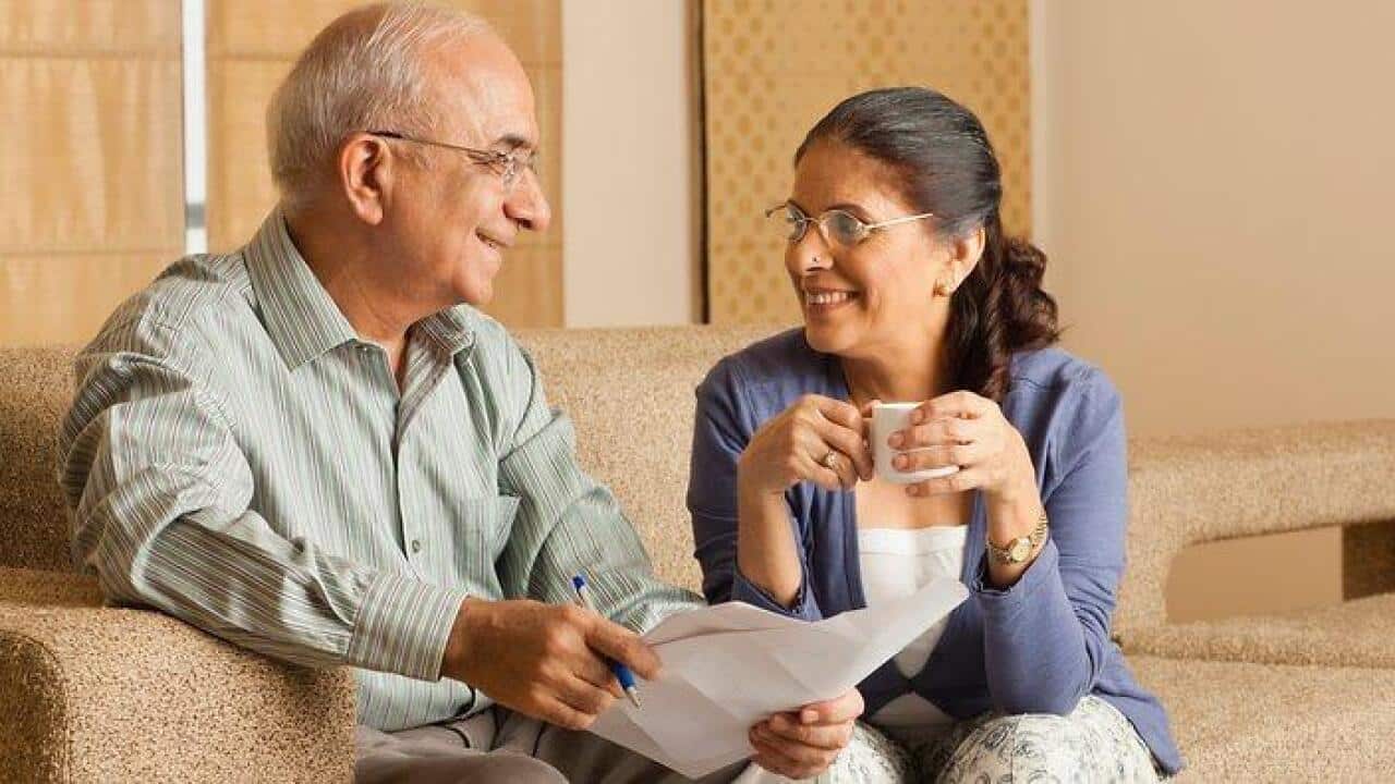 Senior couple working in living room, with laptop on coffee table