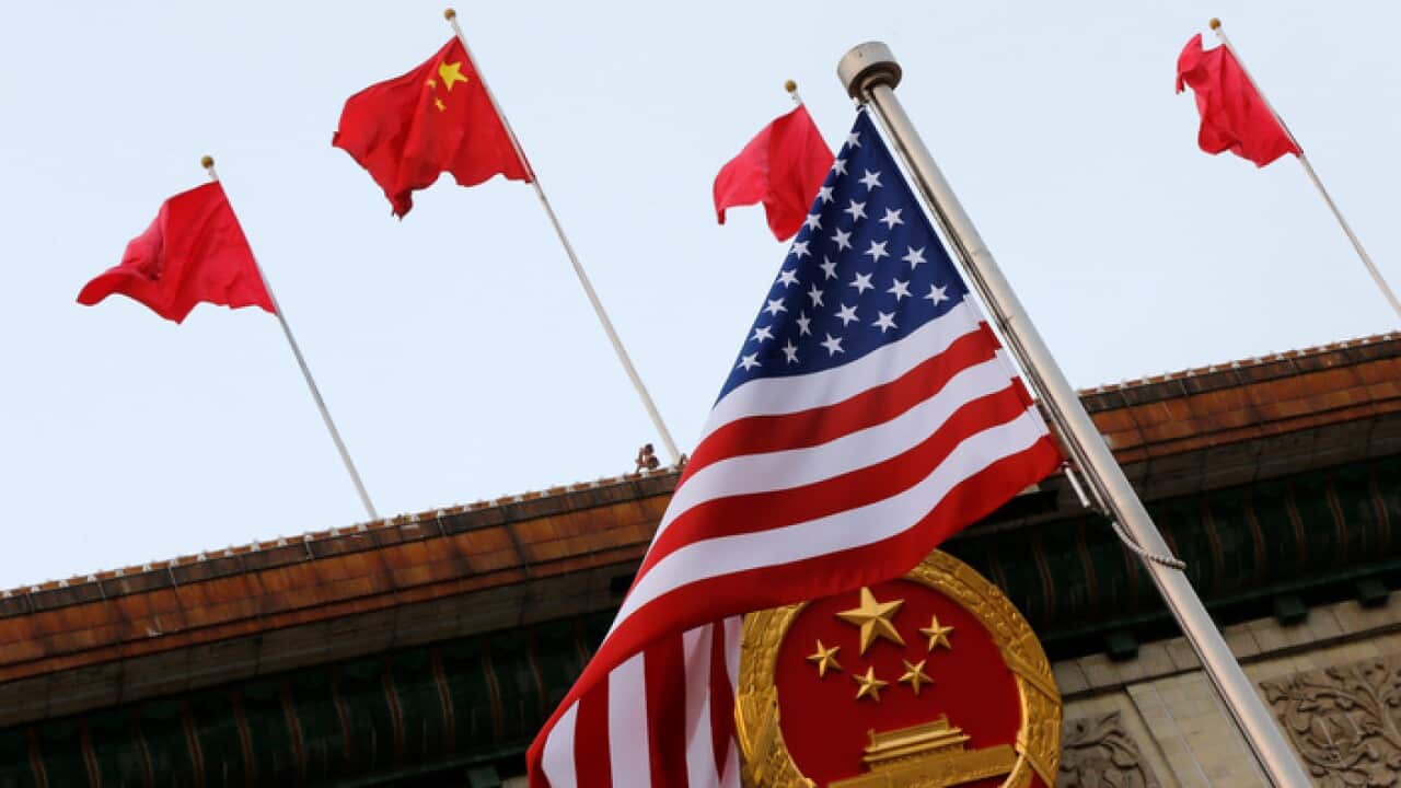 An American flag is flown next to the Chinese national emblem in Beijing, Thursday, Nov. 9, 2017.