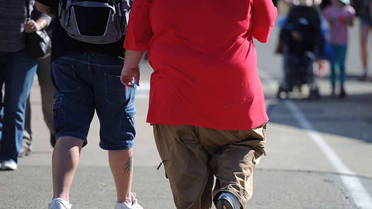 An overweight man walks through Brisbane, Monday, Aug. 12, 2013. (AAP Image/Dave Hunt) NO ARCHIVING