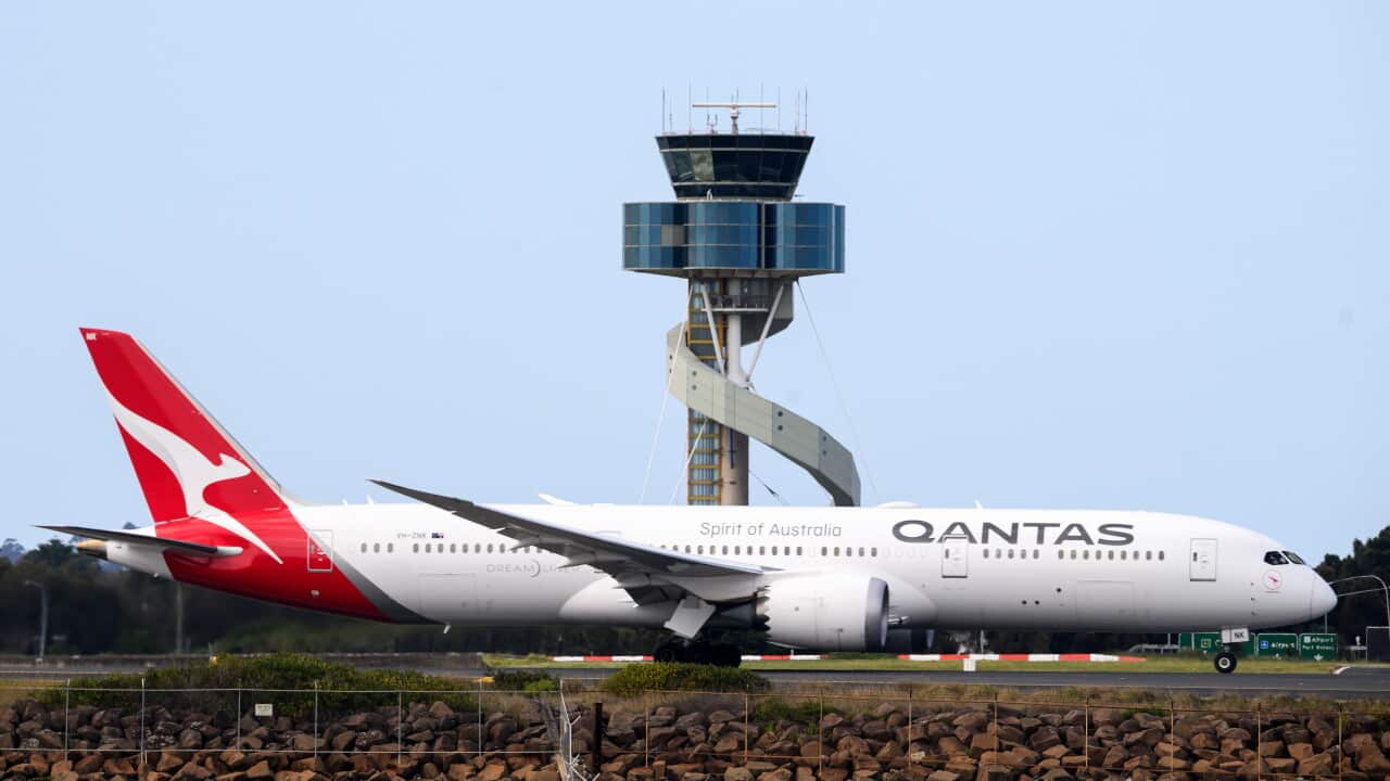 A Qantas plane in front of a control tower