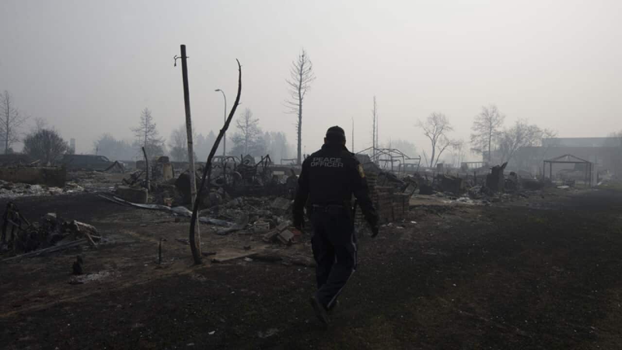 A peace officer walking through smoke in Fort McMurray, Alberta