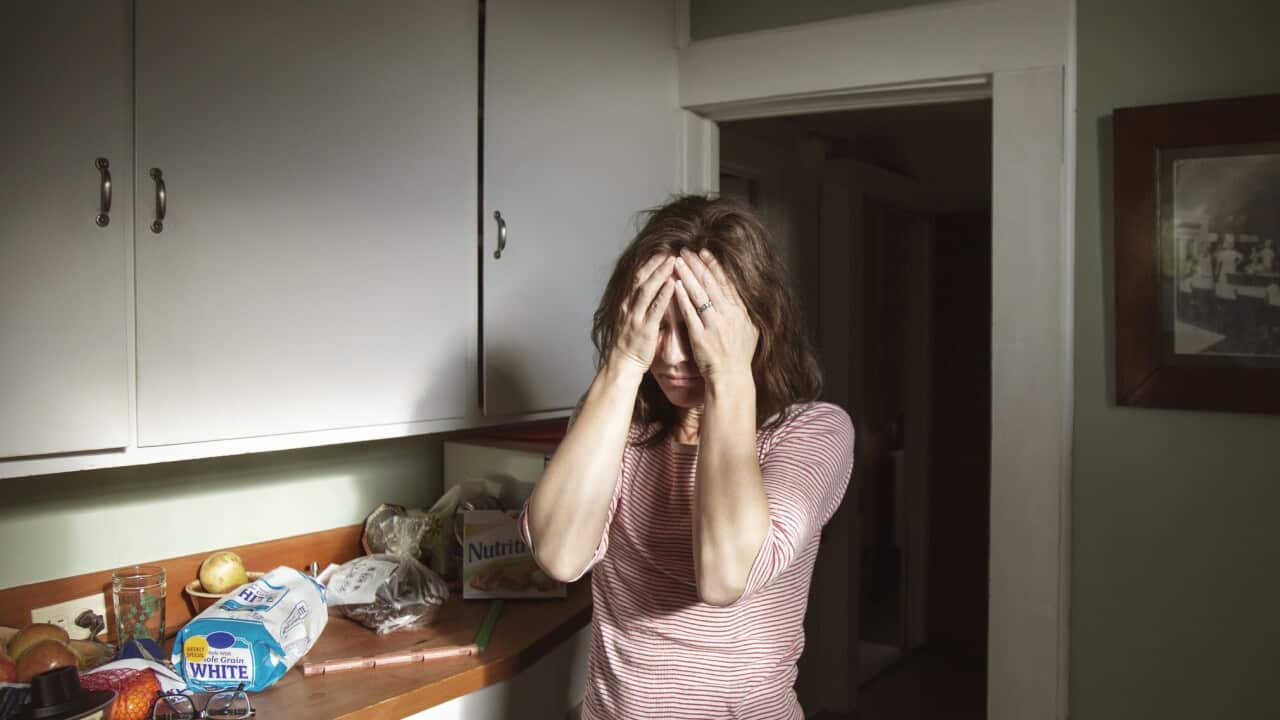 Woman suffering from headache standing in kitchen