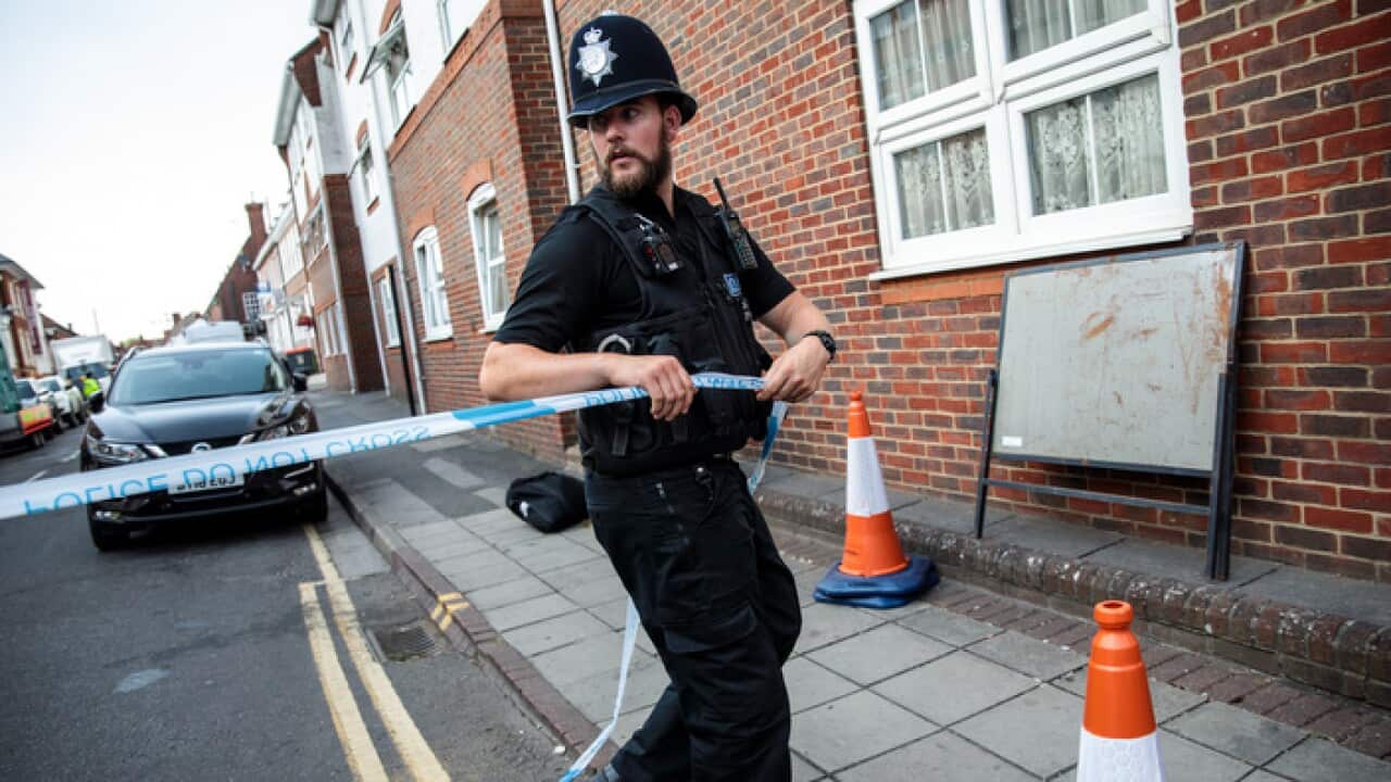A police officer fixes police tape across a street by a supported housing project in Salisbury, UK