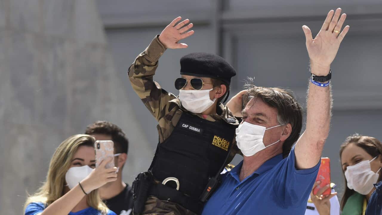 President Bolsonaro carries a child during a protest against Brazil's National Congress to back his open-the-economy drive amid the pandemic, in May.o