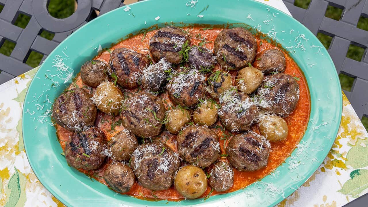 An oval green dish sits on a patterned tablecloth. The dishholds