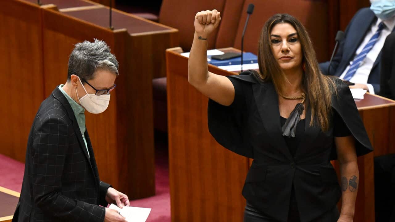 Lidia Thorpe, wearing an all-black outfit, raises her arm during her swearing-in ceremony in the Senate chamber at Parliament House