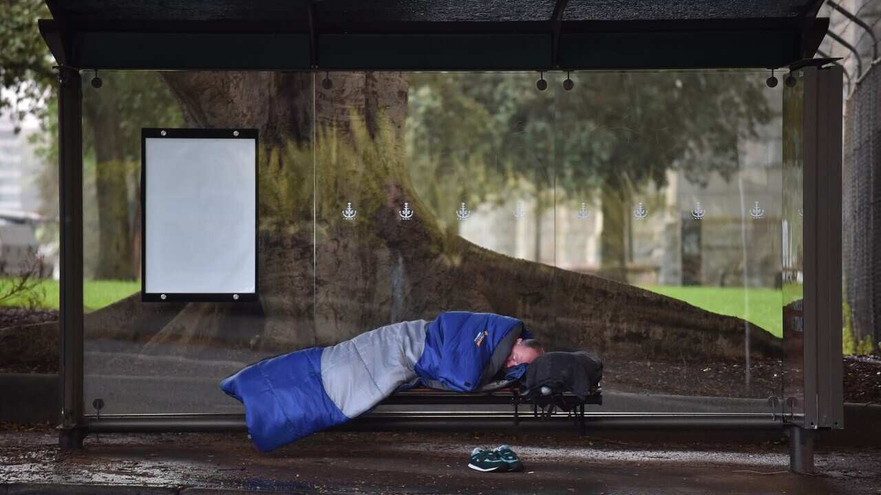 A man sleeping in a bus shelter near Sydney harbour