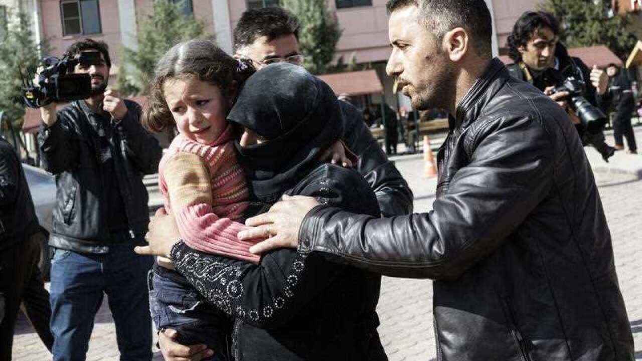 A Turkish man helps a Syrian woman carrying a wounded Syrian girl to a hospital in Kilis, Turkey, Monday, Feb. 15, 2016.