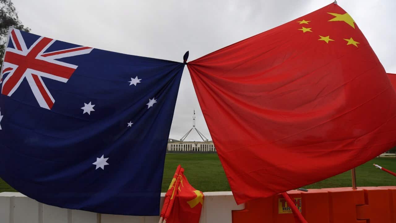 Parliament House is seen behind an Australian and a Chinese flag outside Parliament House in Canberra, Thursday, March 23, 2017. Premier of the State Council of the People's Republic of China Li Keqiang is in Australia on a 5-day official visit.
