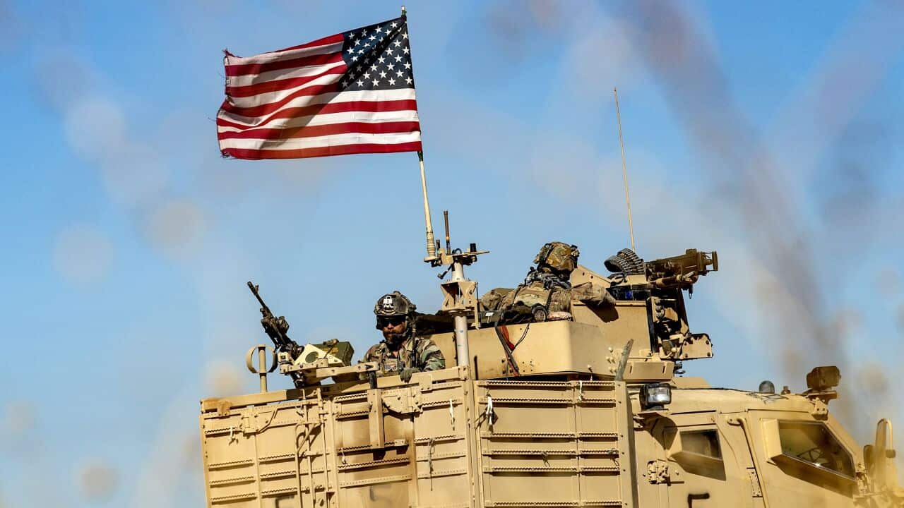 US soldiers sit atop a military vehicle in the Middle East.
