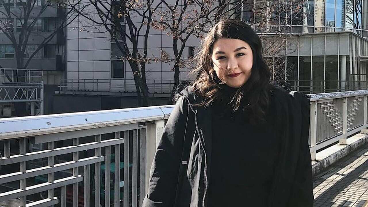 Woman standing on a bridge looking at camera.