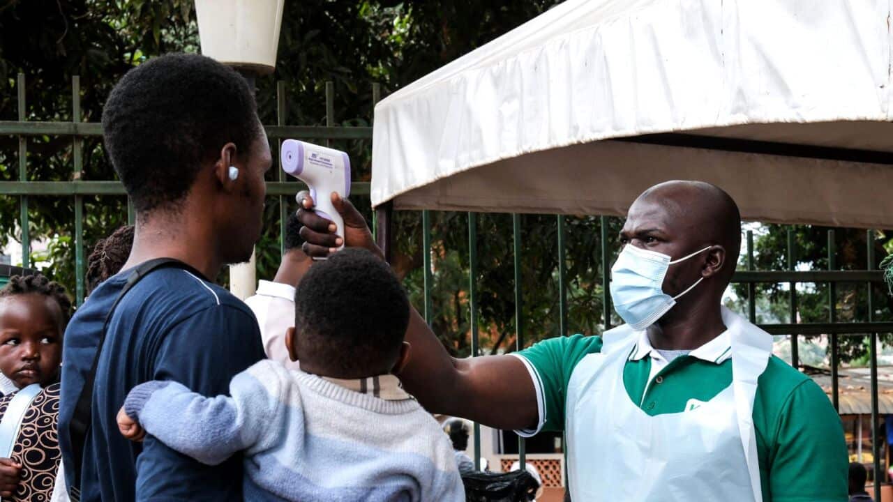 A health official uses a thermometer to screen people in front of Kibuli Muslim Hospital in Kampala, Uganda (AP Photo-Hajarah Nalwadda).jpg