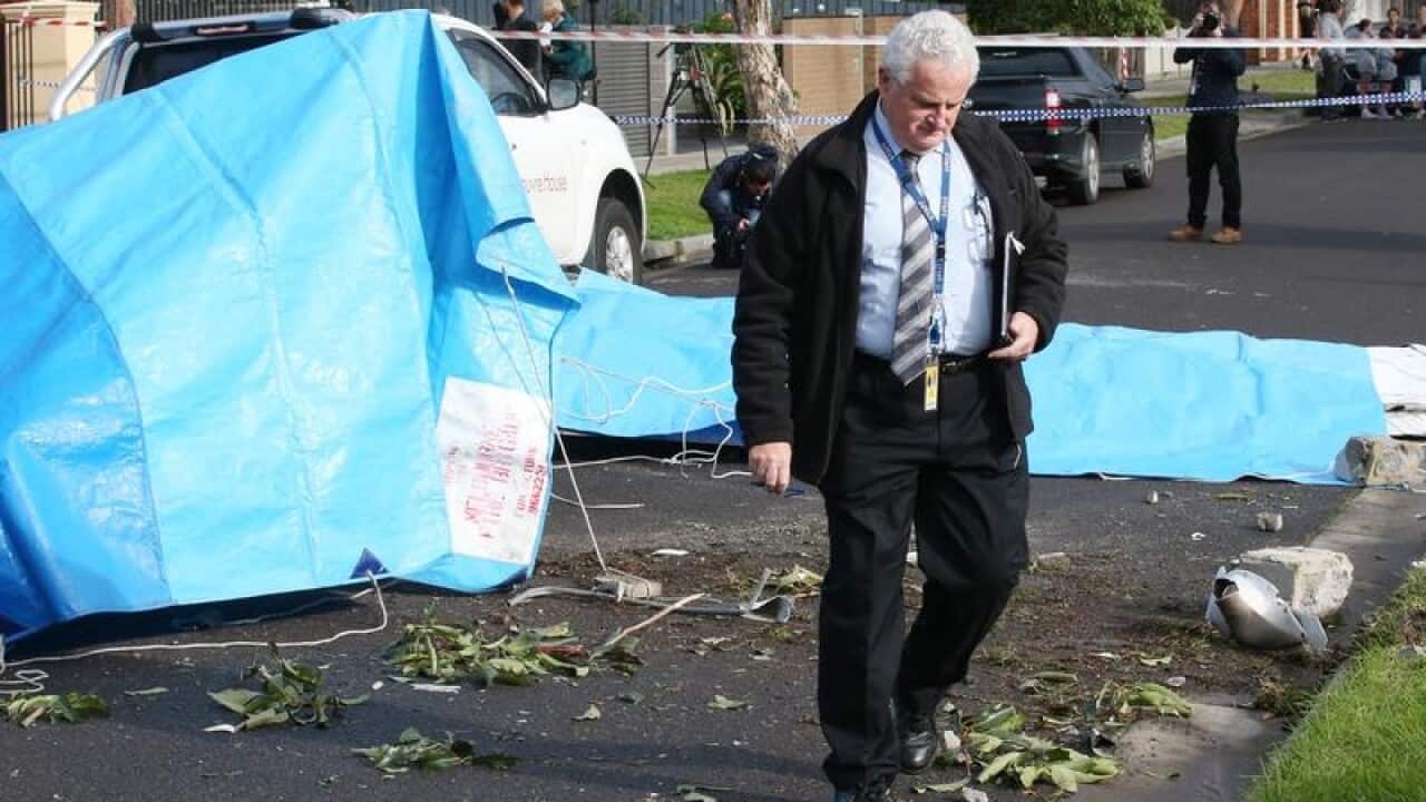 A man wlaks away from the covered wreckage of a light plane
