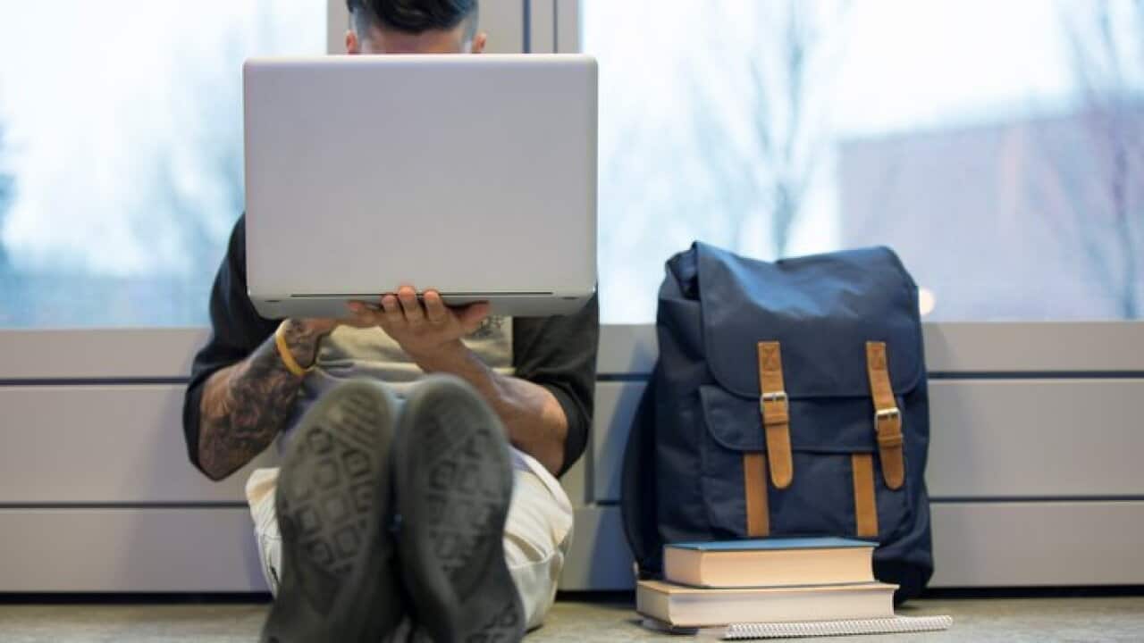 College student using laptop on floor