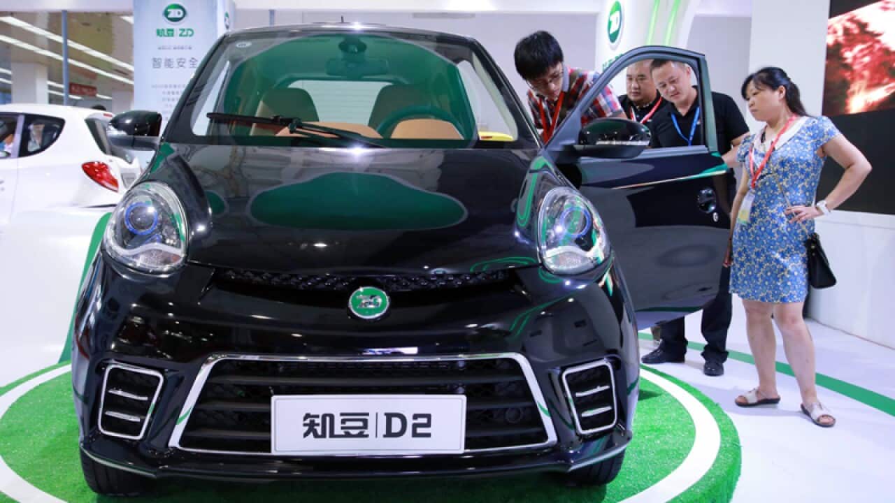 Visitors look at an electric car during an exhibition in Beijing