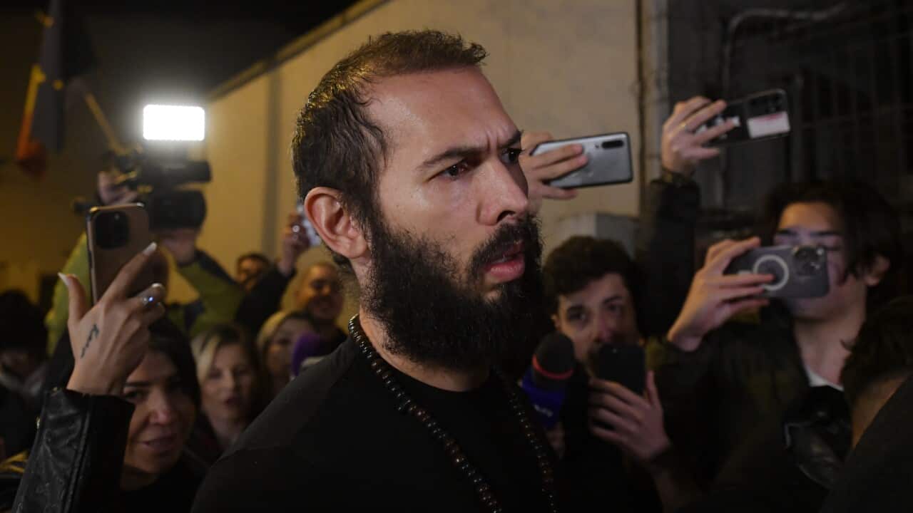 Andrew Tate surrounded by people taking photos with their phones