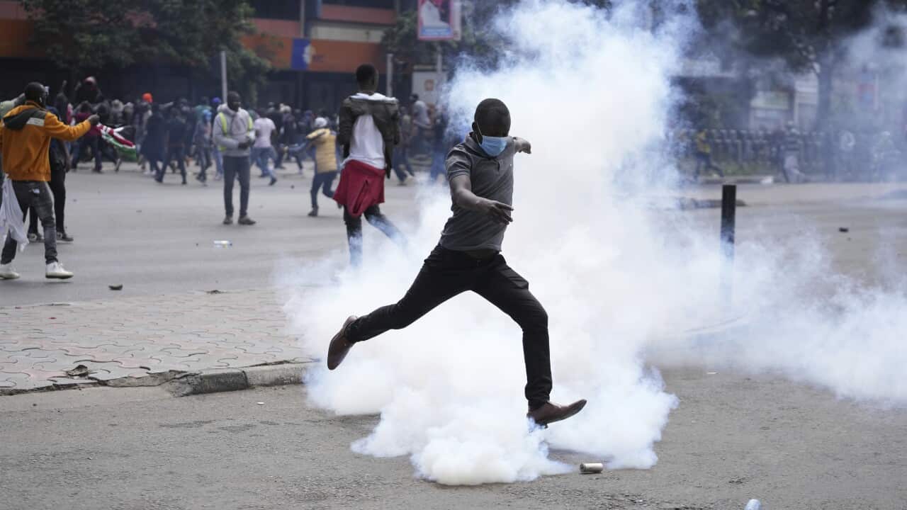 A man kicks back a tear gas grenade towards Kenya anti-riot police during a protest over proposed tax hikes