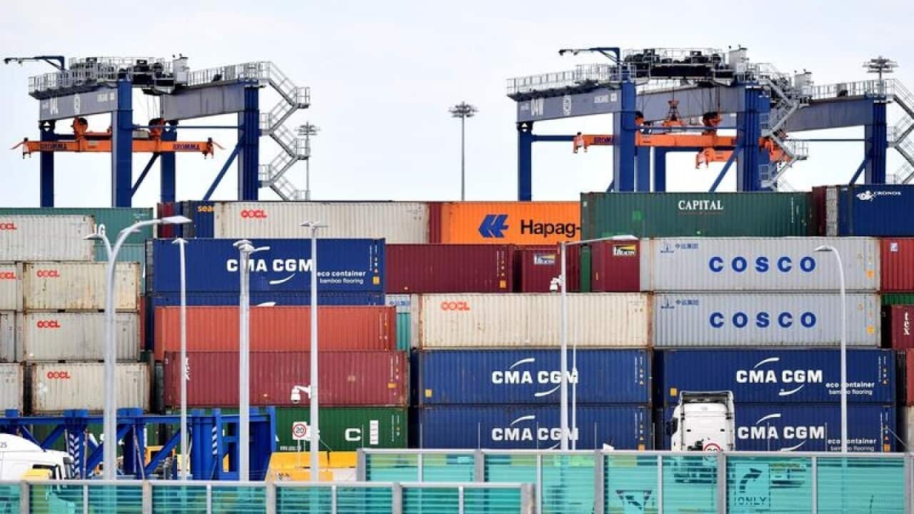 Shipping containers are seen in a container yard.