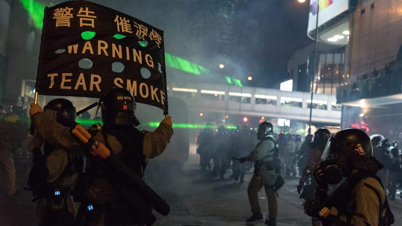 Riot police fire tear gas near a shopping center.