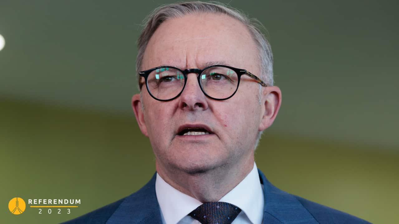 A man wearing a suit and tie who is speaking.