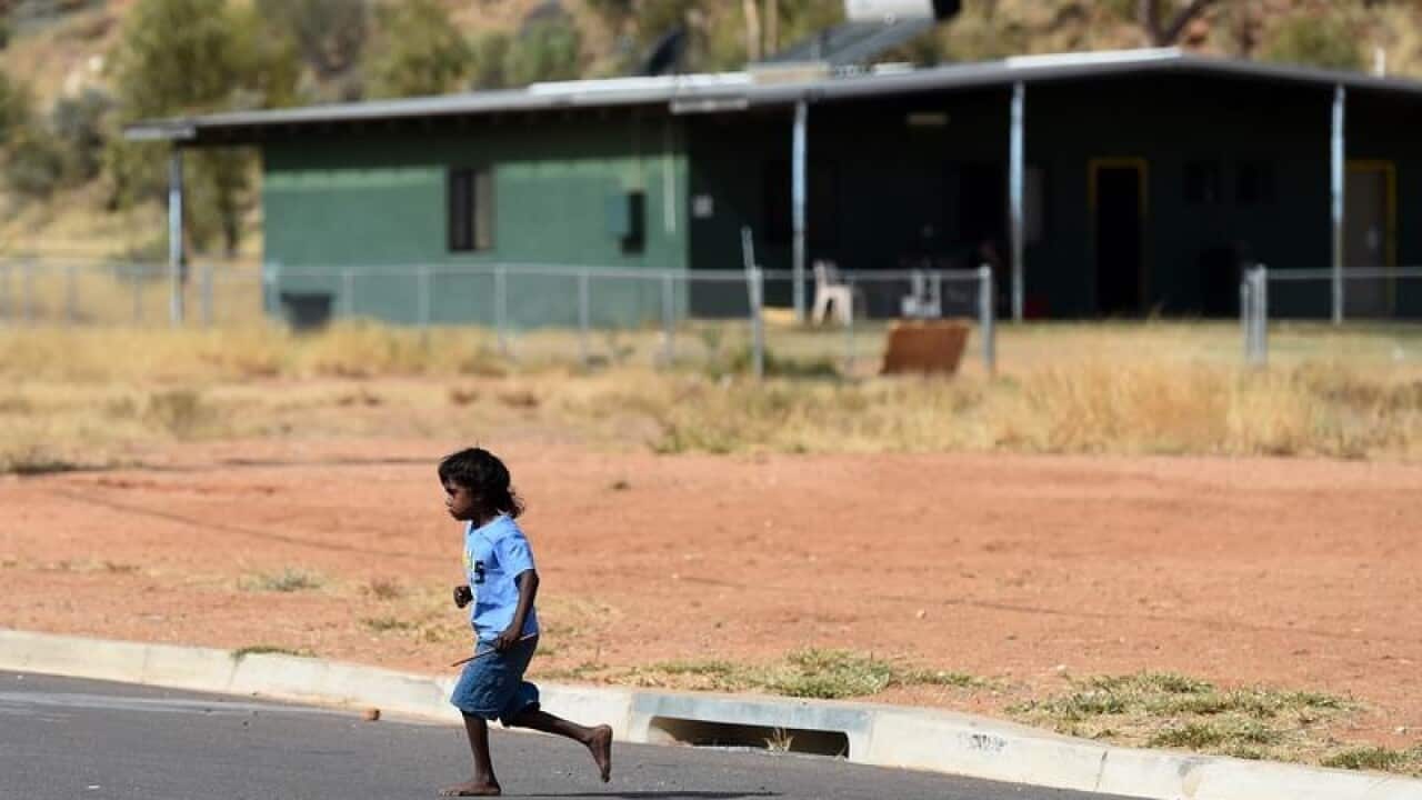 A child runs across a road during play at the Hidden Valley town camp.