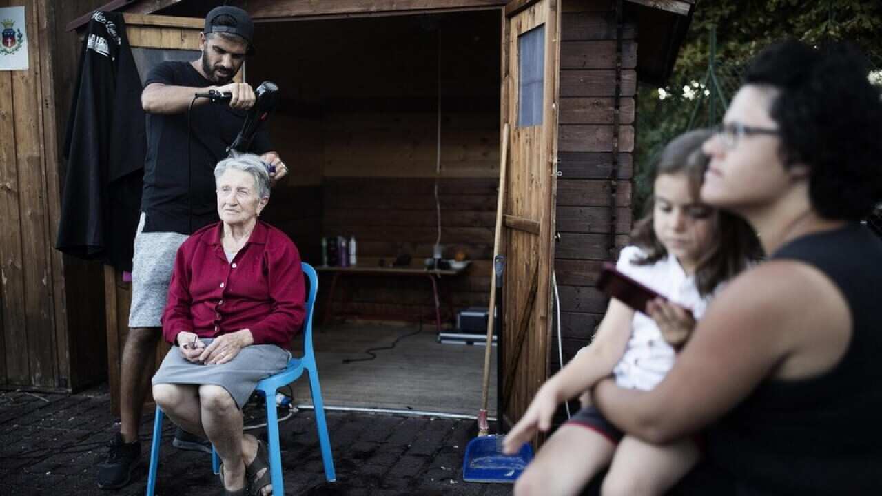 A hairdresser gives a woman a perm at a tent camp in Amatrice