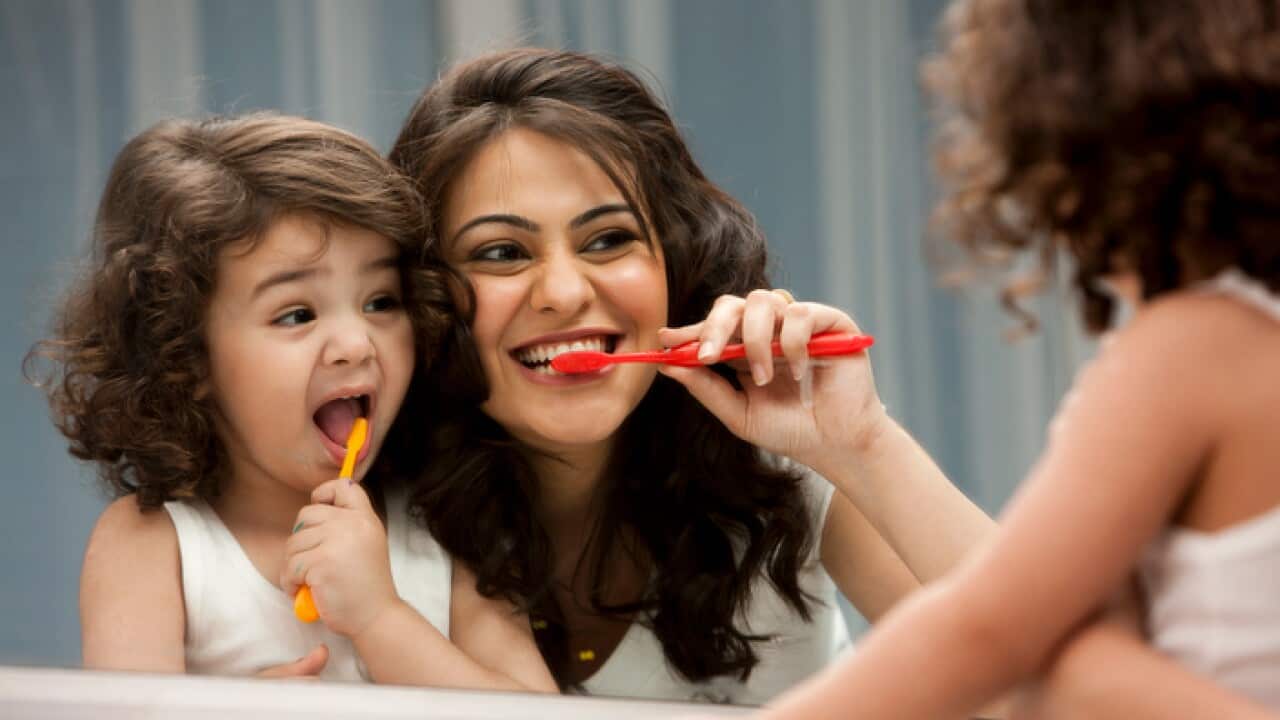 Mother and daughter (2-3) brushing teeth
