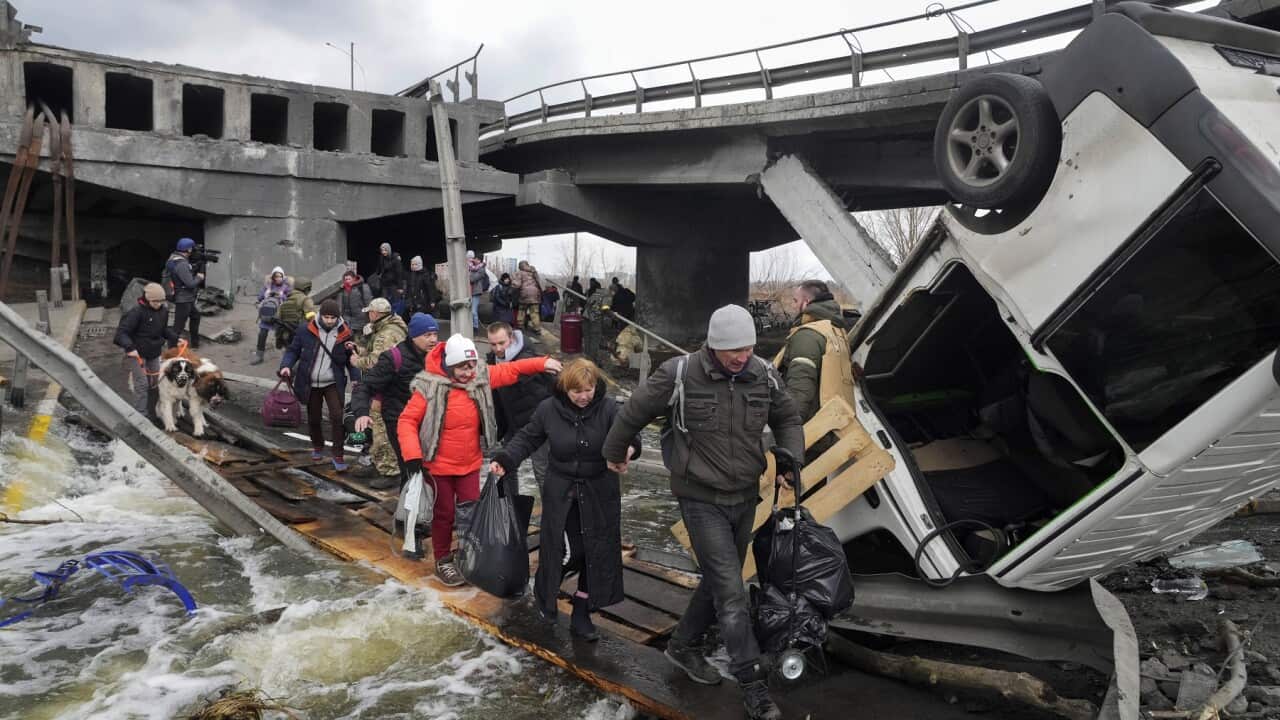 People cross an improvised path under a destroyed bridge while fleeing the town of Irpin close to Kyiv