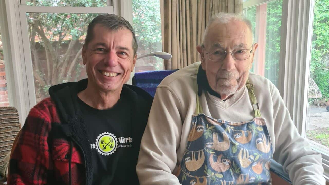 a middle aged man and an old man smile together in a living room