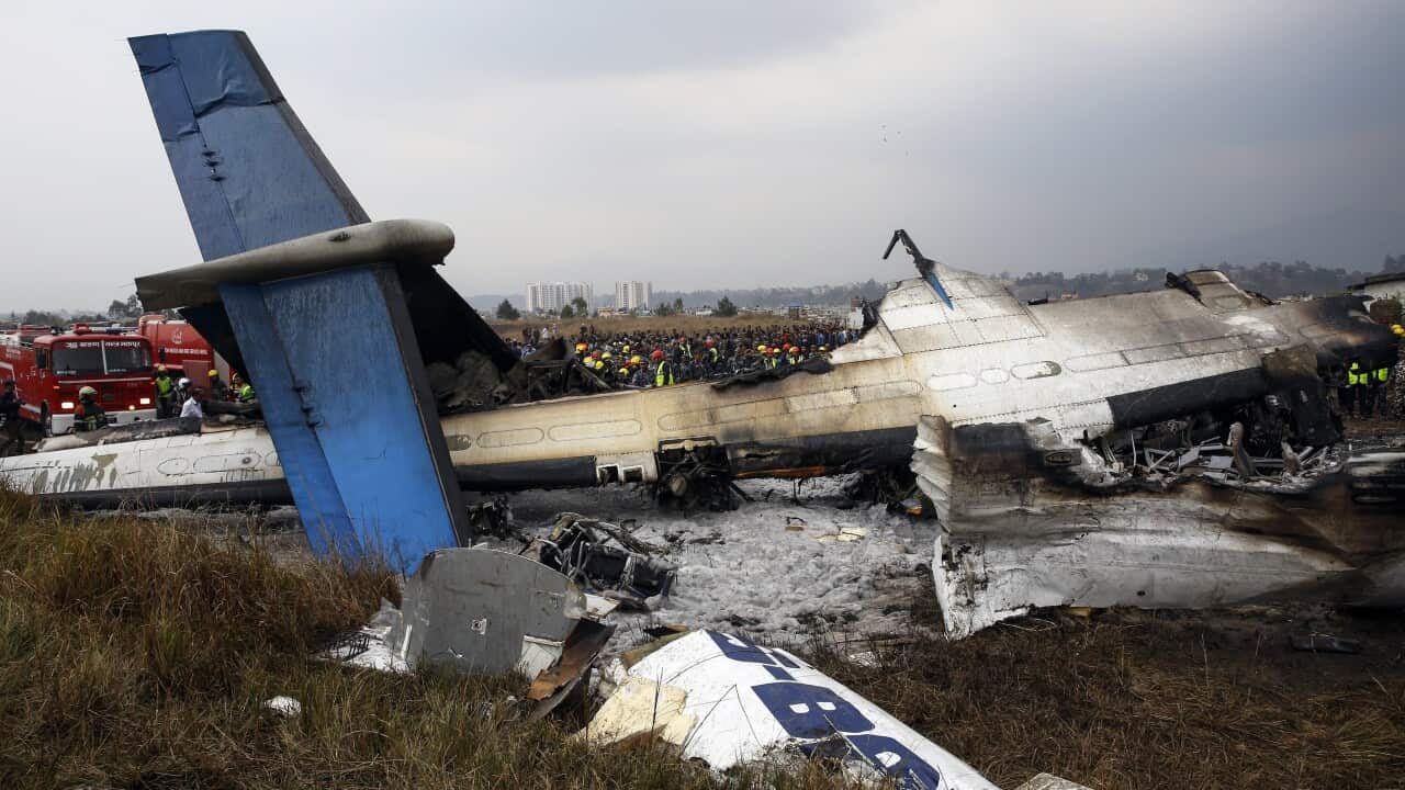Rescue teams next to a wreckage of a plane that crashed at the main airport Tribhuvan International Airport in Kathmandu, Nepal. (AAP).