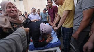A woman weeps over a dead body with other people surrounding them weeping and mourning