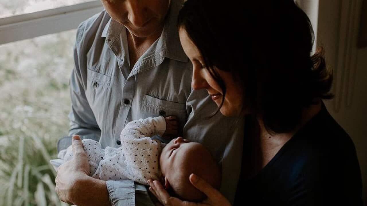 A couple hold their newborn baby.