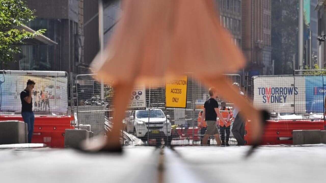 Pedestrians walk past the Sydney CBD Light Rail Project construction.