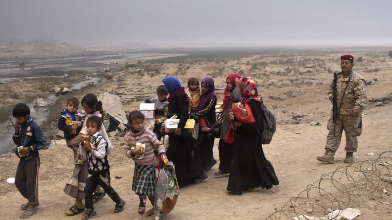 Internally displaced persons clear a checkpoint in Qayara