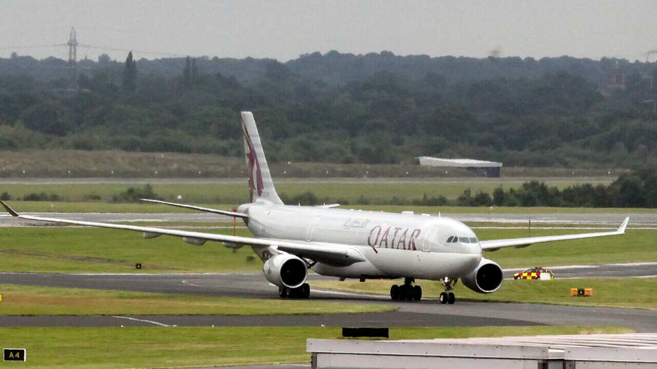 A QATAR aircraft has been escorted into Manchester Airport and a man in a green t-shirt has been taken off the plane after a, what later turned out to be a hoax, bomb threat occurred..