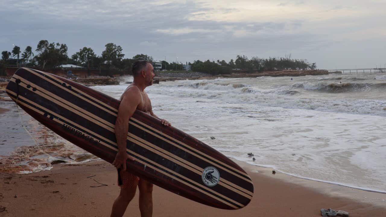 A surfer takes to the water as storms sweep across the top end resulting in wild surf rolls at Nightcliff beach in Darwin.