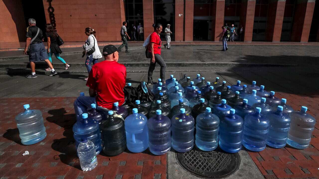 A man remains seated next to large bottles of water in Caracas, Venezuela, 29 March 2019.