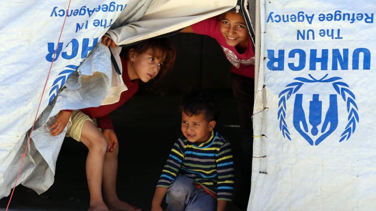 Syrian refugee children look from their tent