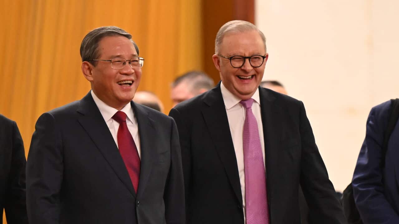 Two men in suits are walking side by side and laughing.
